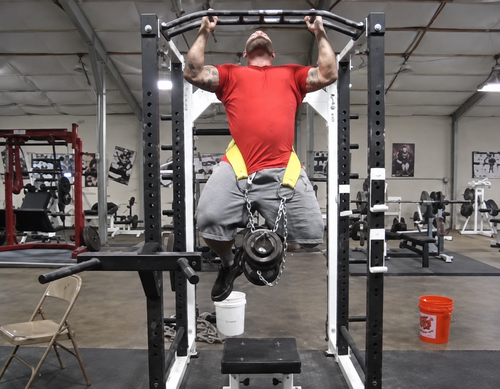 Jim Wendler performing a heavily weighted chin-up with dumbbell suspended from a dip belt