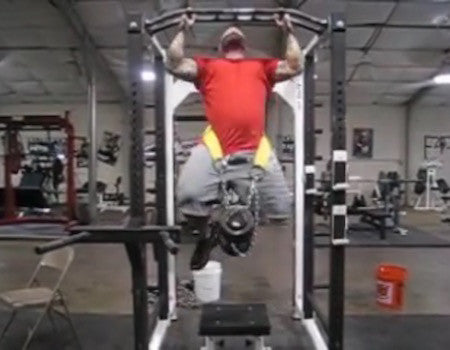 Jim Wendler performing a heavily weighted chin-up with plates suspended from a dip belt