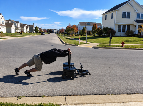 Jim Wendler pushing a heavily loaded Prowler sled on a residential street