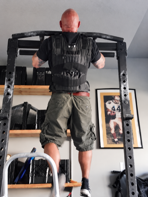 Jim Wendler performing a weighted chin-up during 5/3/1 assistance training