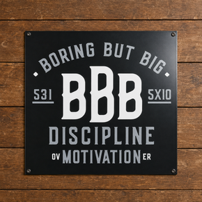 Black Boring But Big aluminum wall sign featuring “Discipline Over Motivation” on a wood background.
