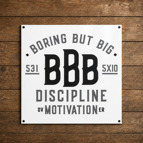 White Boring But Big aluminum wall sign featuring “Discipline Over Motivation” on a wood background.