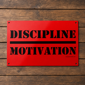 Red Discipline Over Motivation aluminum wall sign with black stencil lettering on a wood background.