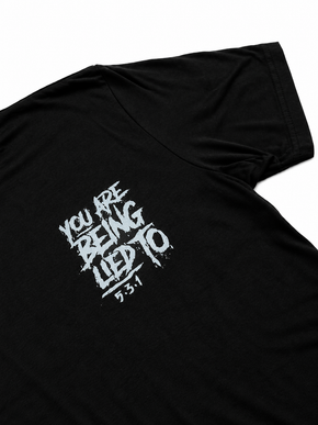 Close-up of the distressed cool-grey You Are Being Lied To design on the black shirt by Jim Wendler.